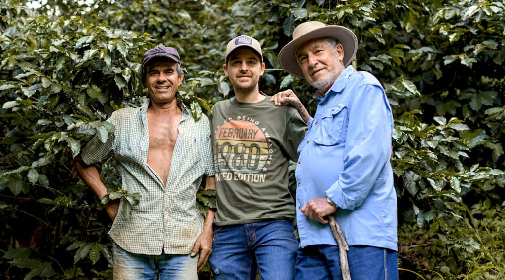 picture of Hatillo Coffee's co-founder, Miguel Echeverri, his specialty coffee farmer, Don Alberto Echeverri and a coffee picker from the Piedra Larga farm with coffee plants in the background