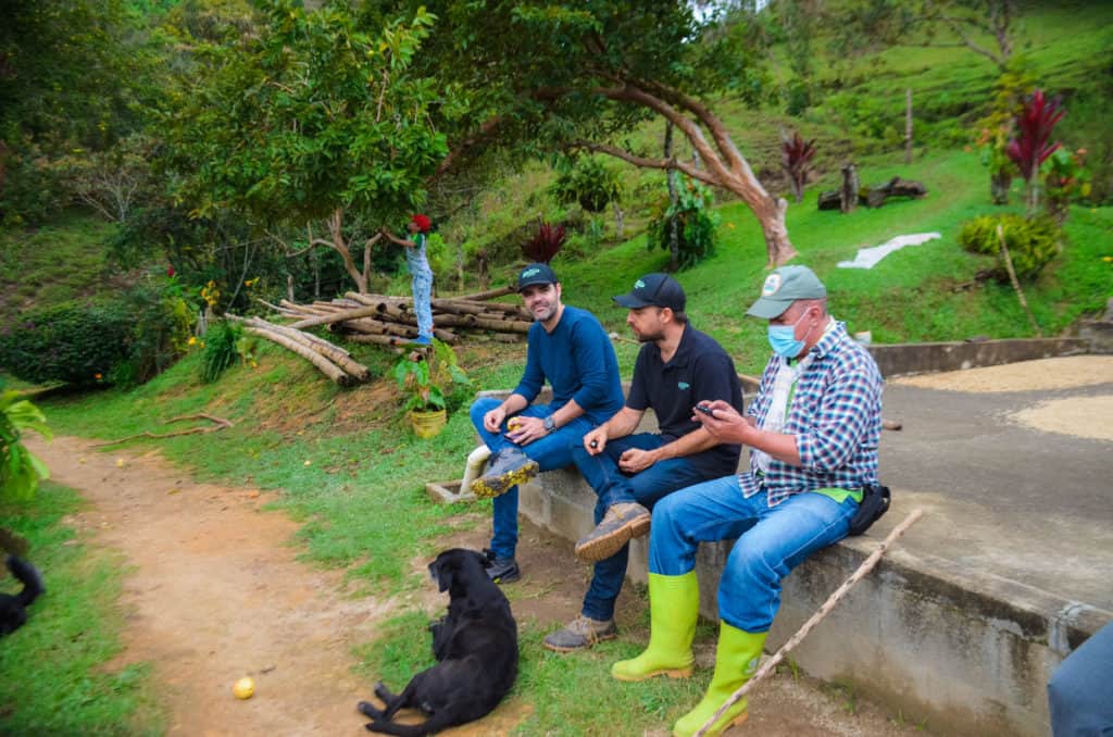 picture showing from left to right, Jaime Rodriguez and Miguel Echeverri, Hatillo Coffee co-founders, and Raul Florez, Colombian coffee farmer in his farm La Teresita near Barbosa Antioquia sitting on a coffee drying bed